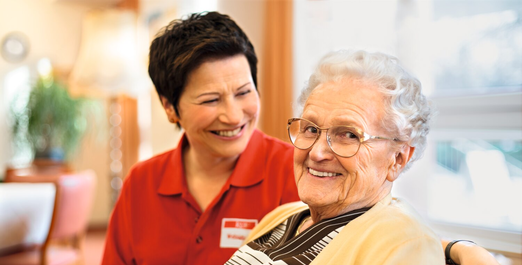 Pflegekraft unterhält sich mit Seniorin