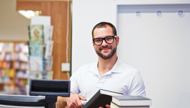 Mitarbeiter scannt Buch an der Kasse 