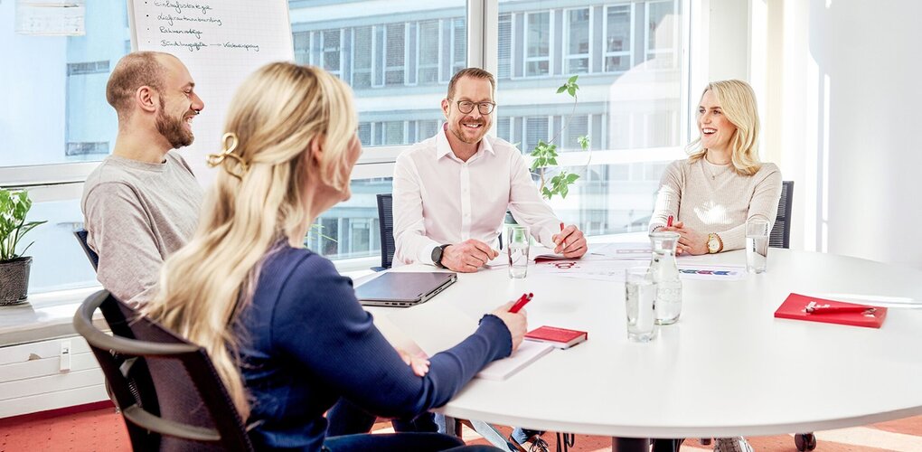 Vier Personen im Meeting mit Flipchart und Notizen