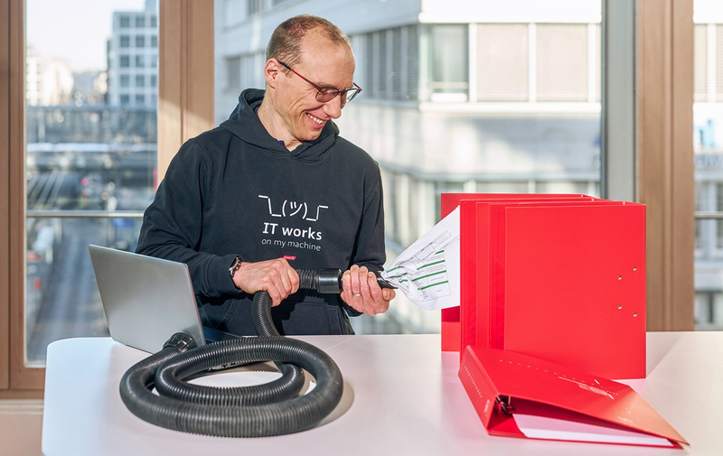Person mit Schlauch und roten Ordnern, symbolische Darstellung von Datenmanagement
