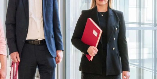 Drei Personen gehen durch ein Bürogebäude mit Unterlagen